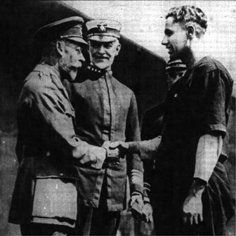 King George shakes hand with Lt. Mims, captain of the army team.  Admiral Sims looks on.