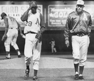 Paige walks off the field with Manager Haywood Sullivan while Diego Segui warms up.